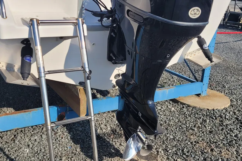 Slide: The Image of 2022 Aquasport 2100 Center Console boat with outboard motor and ladder on gravel. - 53