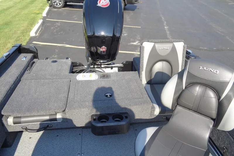 Slide: The Image of 2026 Lund 1775 Adventure SS boat interior with seating and motor, parked on asphalt. - 17