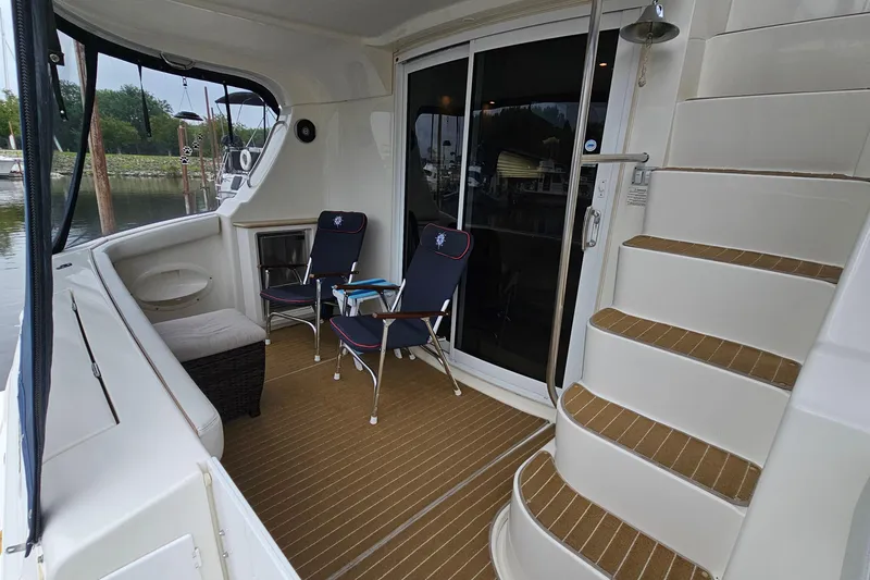 Slide: The Image of 2007 Silverton 38 Sport Bridge yacht deck with chairs and stairs, docked by the water. - 4