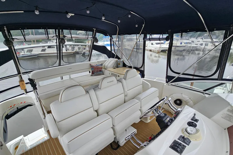 Slide: The Image of 2007 Silverton 38 Sport Bridge interior with white seating and helm, docked at marina. - 7