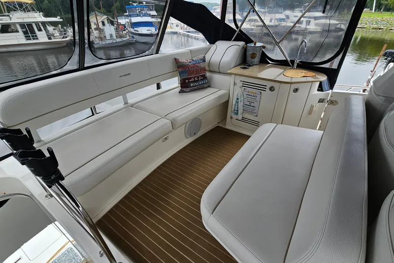 Slide: The Image of 2007 Silverton 38 Sport Bridge interior with white seating and kitchenette, docked at marina. - 9