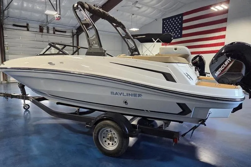 Slide: The Image of 2025 Bayliner VR5 OB boat on trailer in showroom with American flag. - 2