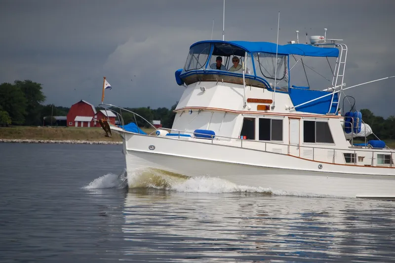 Slide: The Image of 1985 Grand Banks 42 Classic yacht cruising on calm waters with a red barn in the background. - 1