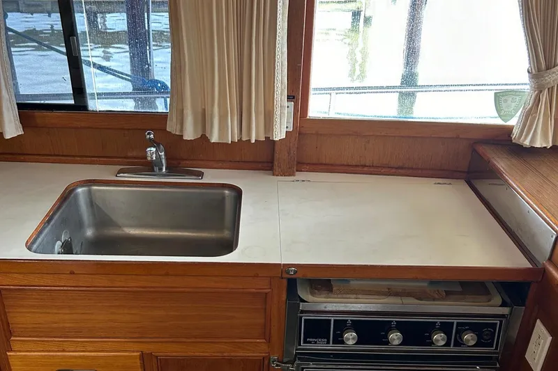 Slide: The Image of 1985 Grand Banks 42 Classic yacht kitchen with sink and stove, featuring wooden cabinetry. - 22