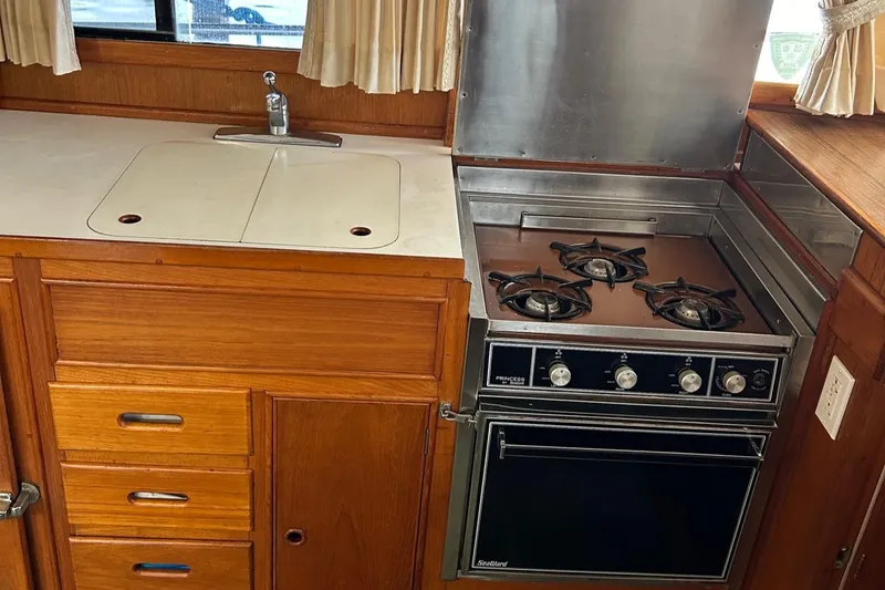 Slide: The Image of 1985 Grand Banks 42 Classic kitchen with stove, sink, and wooden cabinetry. - 23