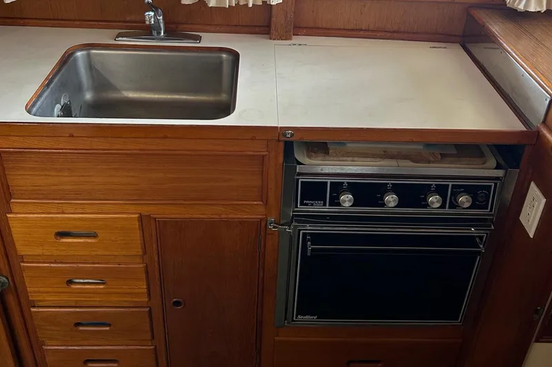 Slide: The Image of 1985 Grand Banks 42 Classic kitchen with sink, stove, and wooden cabinetry. - 24