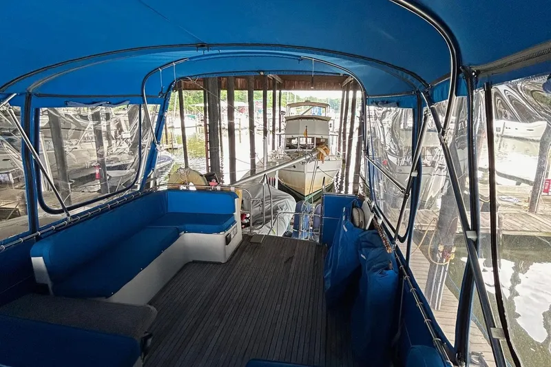 Slide: The Image of 1985 Grand Banks 42 Classic yacht interior with blue canopy and seating, docked in a marina. - 32