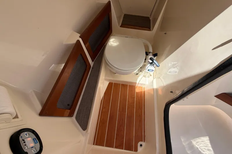 Slide: The Image of 2019 Grady-White Freedom 235 boat interior with toilet and wooden flooring. - 15