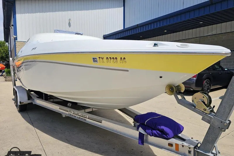 Slide: The Image of 2005 Baja 245 boat on trailer, white and yellow design, parked outside a building. - 13