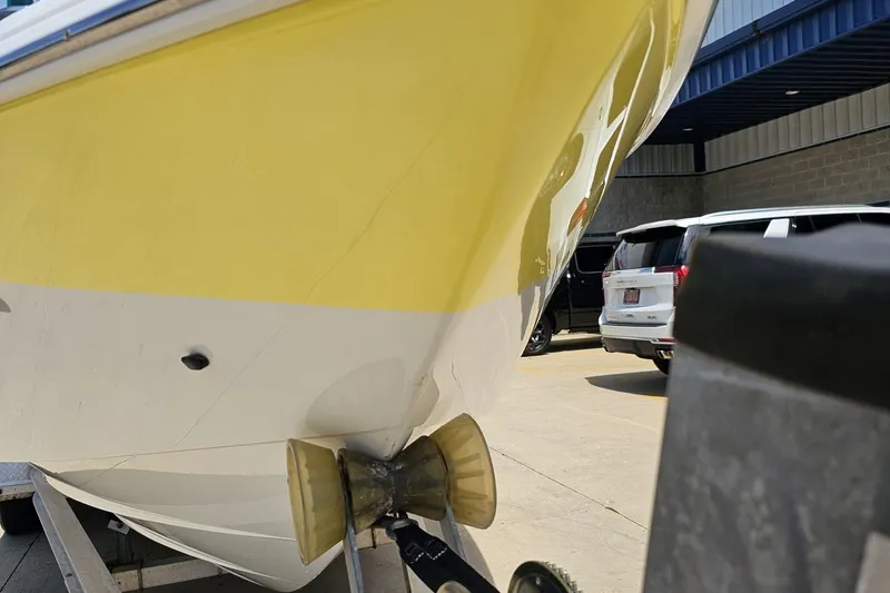 Slide: The Image of Yellow and white 2005 Baja 245 boat on trailer, parked near vehicles. - 14