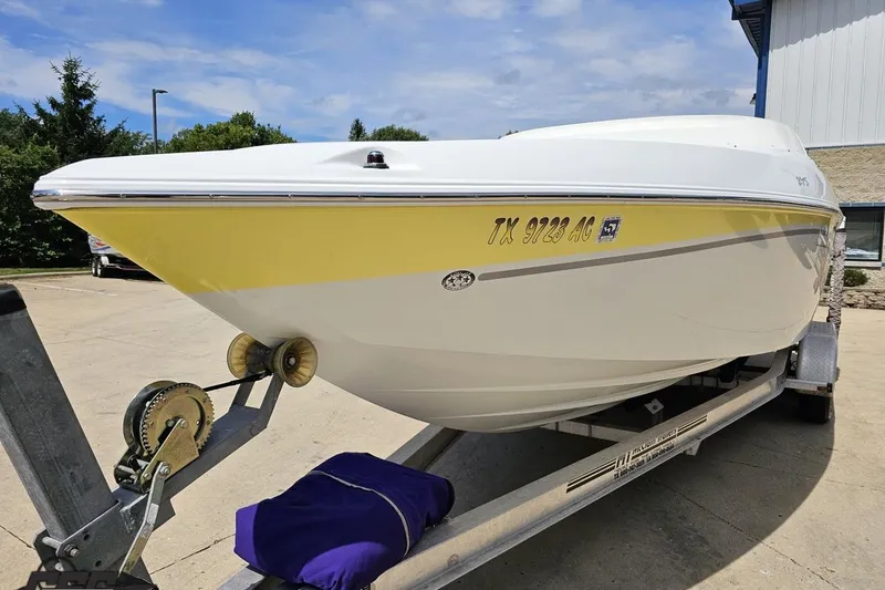 Slide: The Image of 2005 Baja 245 boat on trailer, yellow and white hull, parked outdoors. - 16