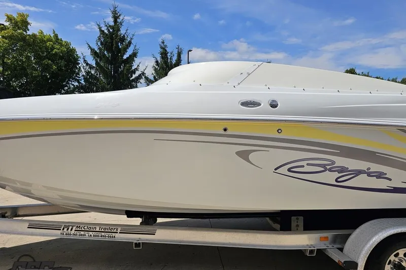 Slide: The Image of 2005 Baja 245 boat on trailer, white with yellow accents, parked outdoors. - 19