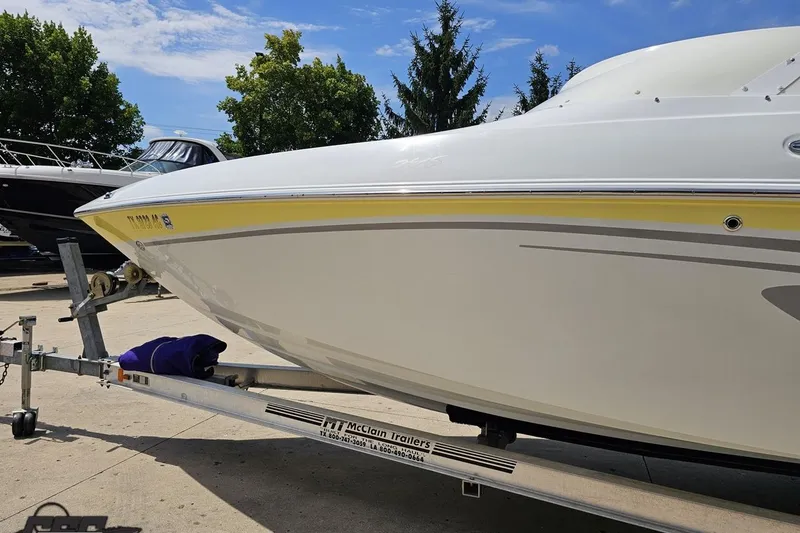 Slide: The Image of 2005 Baja 245 boat on trailer, white with yellow stripe, parked outdoors. - 20