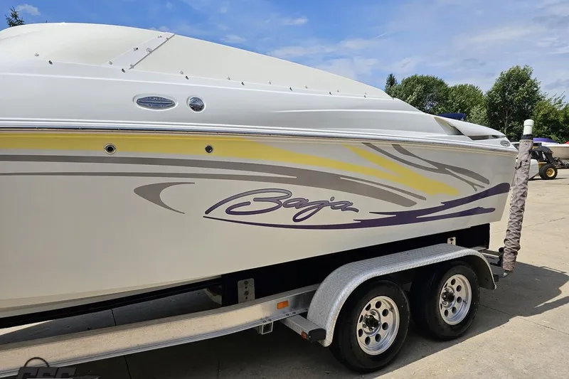 Slide: The Image of 2005 Baja 245 boat on trailer with colorful graphics, parked outdoors. - 21