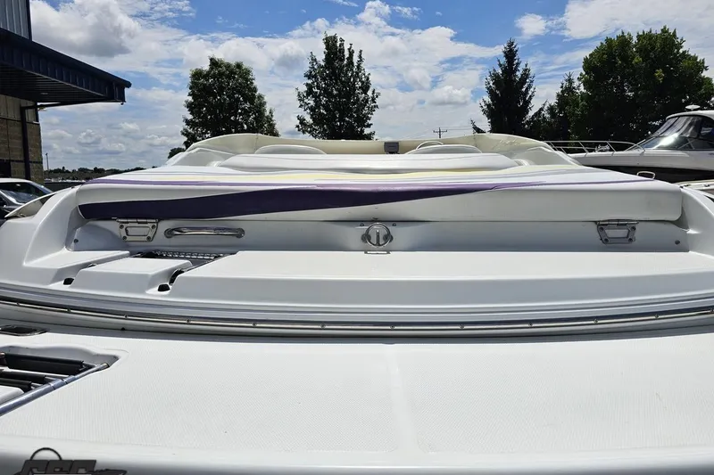 Slide: The Image of 2005 Baja 245 boat rear view with white and purple seating under a blue sky. - 31
