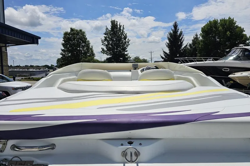Slide: The Image of 2005 Baja 245 boat with colorful upholstery, parked outdoors under a blue sky. - 32