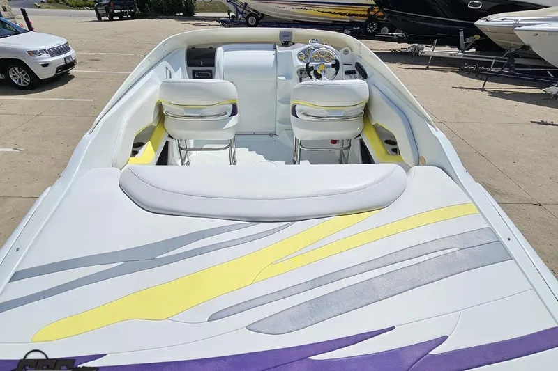 Slide: The Image of 2005 Baja 245 boat interior with white, yellow, and purple seating and dashboard. - 34