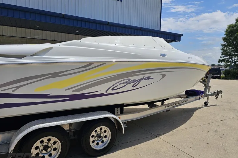 Slide: The Image of 2005 Baja 245 boat on trailer, white with colorful graphics, parked outdoors. - 9