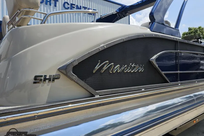 Slide: The Image of 2016 Manitou 23 Legacy boat with sleek design and SHP logo, docked at a port. - 10