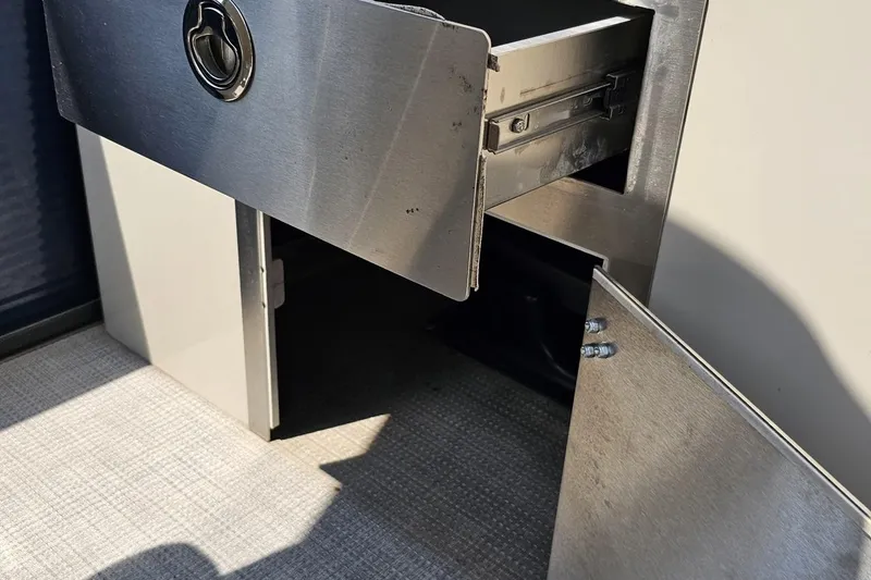 Slide: The Image of Open storage compartment in 2016 Manitou 23 Legacy boat, featuring stainless steel finish. - 100