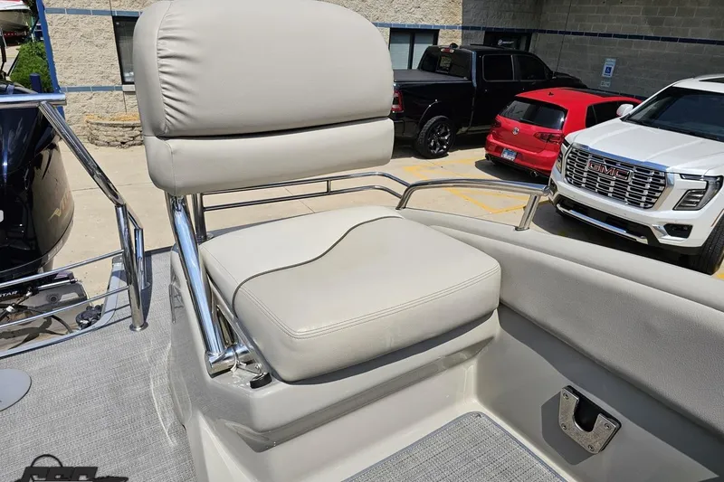 Slide: The Image of 2016 Manitou 23 Legacy boat seat with chrome accents, parked near vehicles. - 109