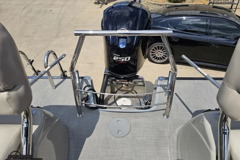 Slide: The Image of 2016 Manitou 23 Legacy boat with Yamaha 250 engine, parked beside a black car. - 113