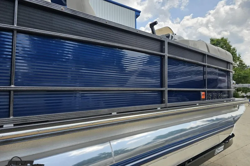 Slide: The Image of 2016 Manitou 23 Legacy pontoon boat with blue and silver exterior, docked outdoors. - 12