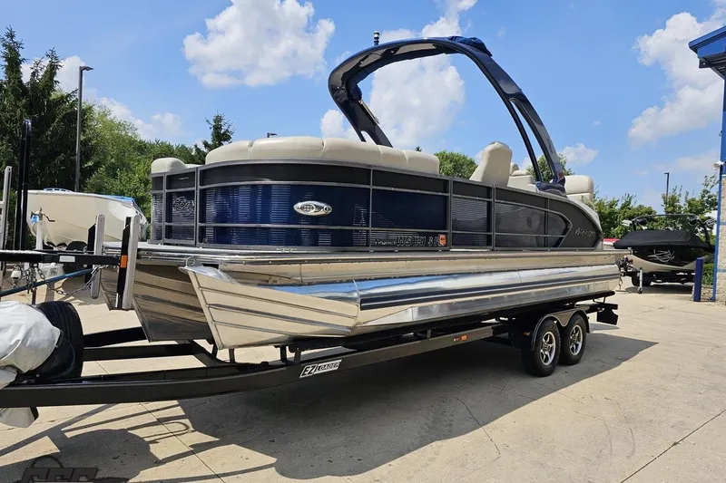 Slide: The Image of 2016 Manitou 23 Legacy pontoon boat on trailer under blue sky. - 23