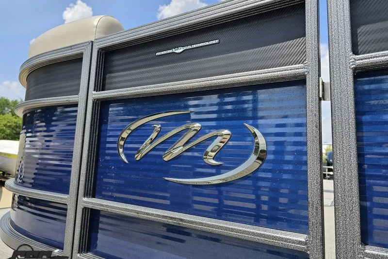 Slide: The Image of 2016 Manitou 23 Legacy pontoon boat with blue and silver detailing under a clear sky. - 28