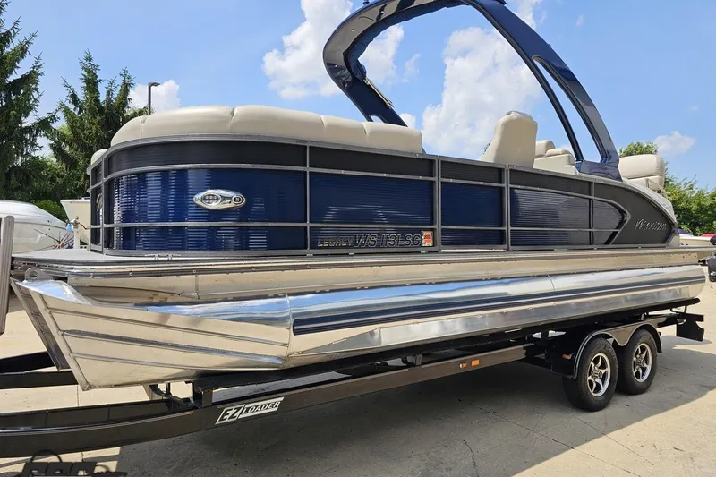 Slide: The Image of 2016 Manitou 23 Legacy pontoon boat on trailer, blue and silver design. - 29