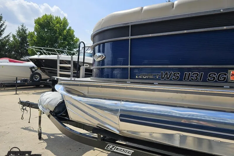 Slide: The Image of 2016 Manitou 23 Legacy pontoon boat on trailer, parked outdoors under a clear sky. - 30