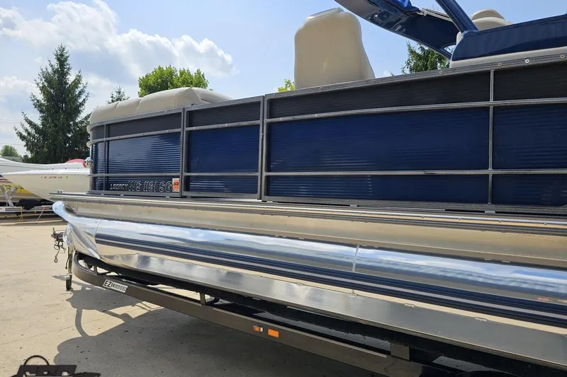 Slide: The Image of 2016 Manitou 23 Legacy pontoon boat on trailer, blue exterior, sunny day. - 31