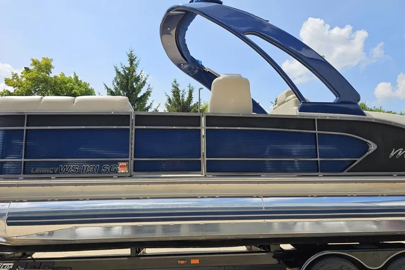 Slide: The Image of 2016 Manitou 23 Legacy pontoon boat with blue and silver design, parked outdoors. - 34