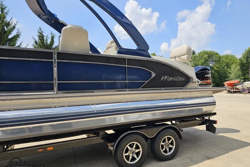 Slide: The Image of 2016 Manitou 23 Legacy pontoon boat on trailer, blue and silver design, outdoors. - 35