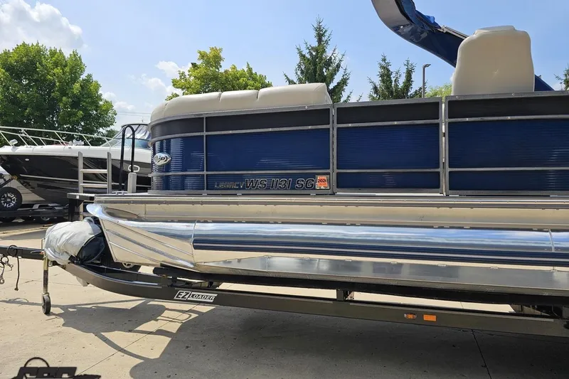Slide: The Image of 2016 Manitou 23 Legacy pontoon boat on trailer, blue exterior, sunny day. - 36