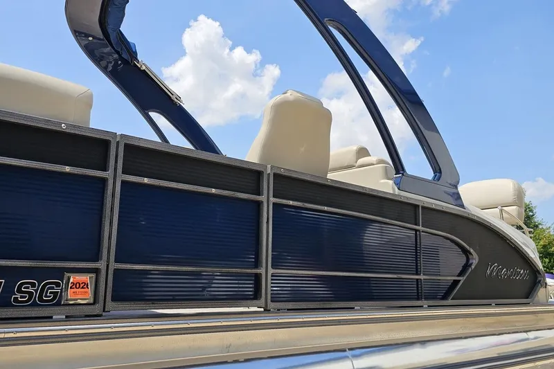 Slide: The Image of 2016 Manitou 23 Legacy pontoon boat with blue exterior and beige seating under a clear sky. - 38