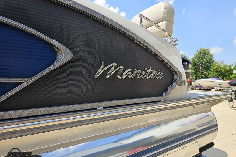 Slide: The Image of 2016 Manitou 23 Legacy boat with sleek design and metallic accents under a clear blue sky. - 39