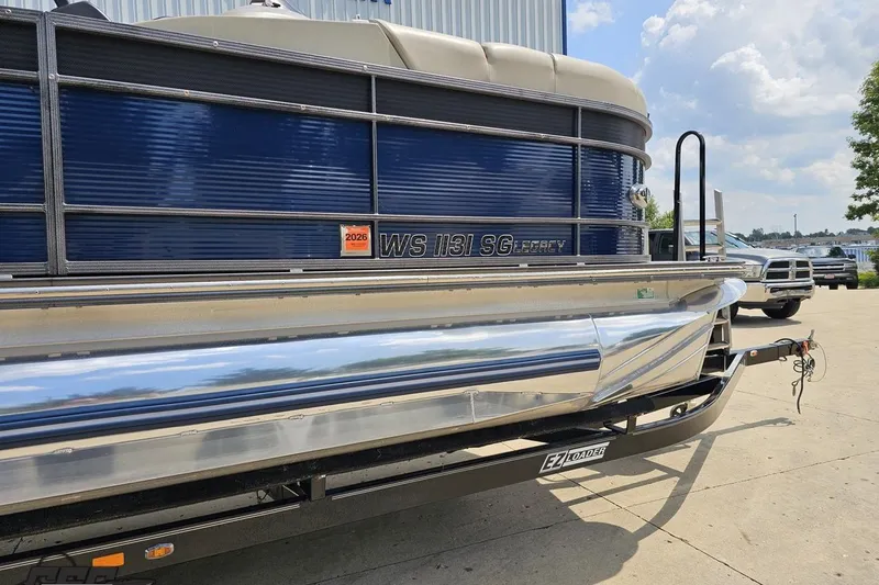 Slide: The Image of 2016 Manitou 23 Legacy pontoon boat on trailer, blue exterior, sunny day. - 4