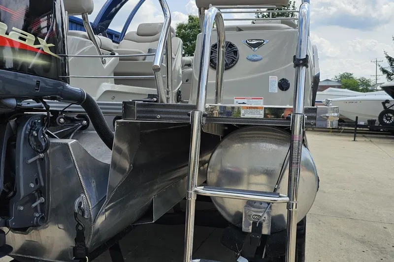 Slide: The Image of 2016 Manitou 23 Legacy boat with ladder and motor, parked outdoors. - 48