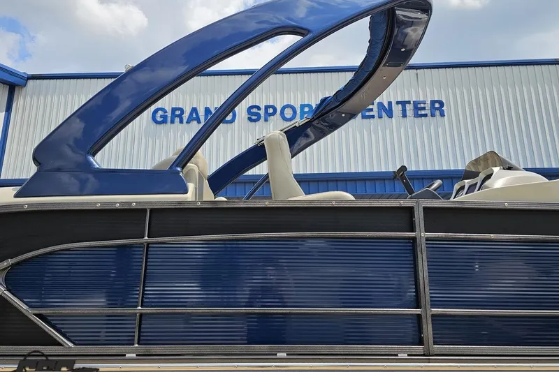 Slide: The Image of 2016 Manitou 23 Legacy boat at Grand Sport Center, featuring sleek blue design. - 5