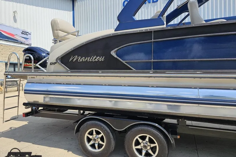 Slide: The Image of 2016 Manitou 23 Legacy pontoon boat on trailer, featuring sleek blue and silver design. - 6