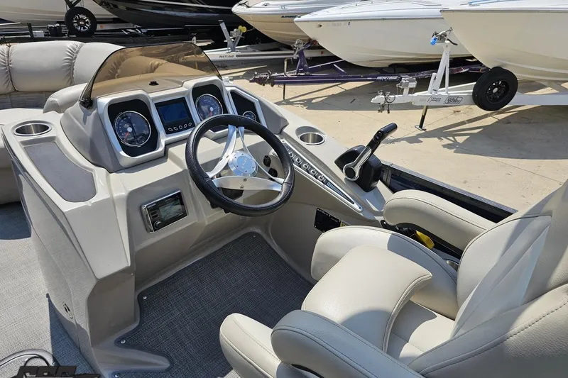 Slide: The Image of 2016 Manitou 23 Legacy boat dashboard with steering wheel and control panel. - 65