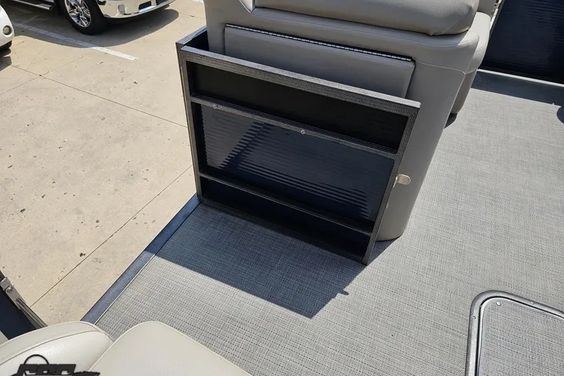 Slide: The Image of 2016 Manitou 23 Legacy boat interior storage compartment with gray seating and flooring. - 73