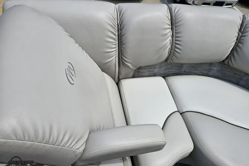 Slide: The Image of 2016 Manitou 23 Legacy boat interior with plush gray seating and armrest. - 85