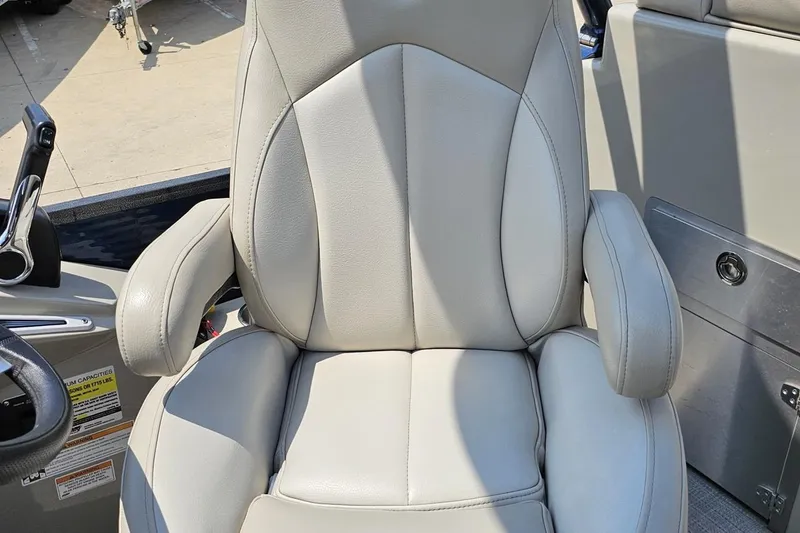 Slide: The Image of 2016 Manitou 23 Legacy boat seat with armrests, featuring sleek gray upholstery. - 92