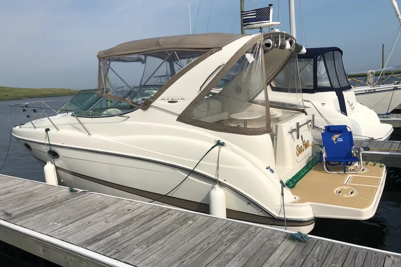 Slide: The Image of 2003 Maxum 2700 SCR boat docked, featuring a beige canopy and sleek design. - 2