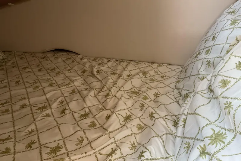 Slide: The Image of Cozy bed with palm-patterned bedding inside a 2003 Maxum 2700 SCR boat cabin. - 23