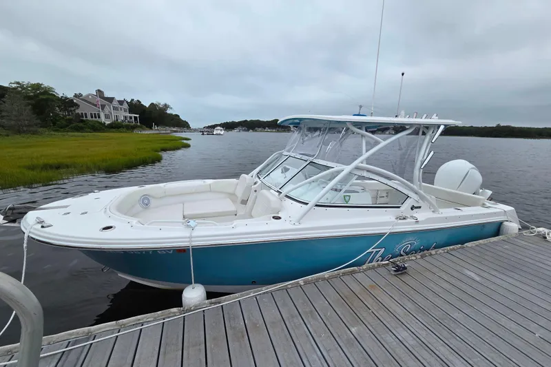 Slide: The Image of 2022 Edgewater 248 CX boat docked by a scenic waterfront. - 0