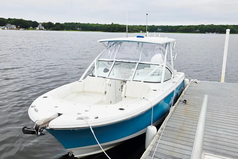 Slide: The Image of 2022 Edgewater 248 CX boat docked on a calm lake, featuring a sleek blue and white design. - 1