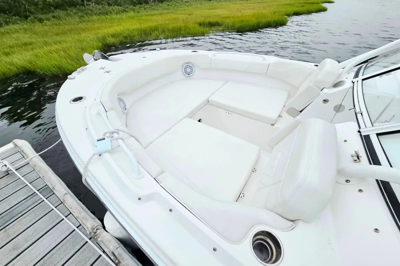 Slide: The Image of 2022 Edgewater 248 CX boat with white seating, docked by grassy shoreline. - 11